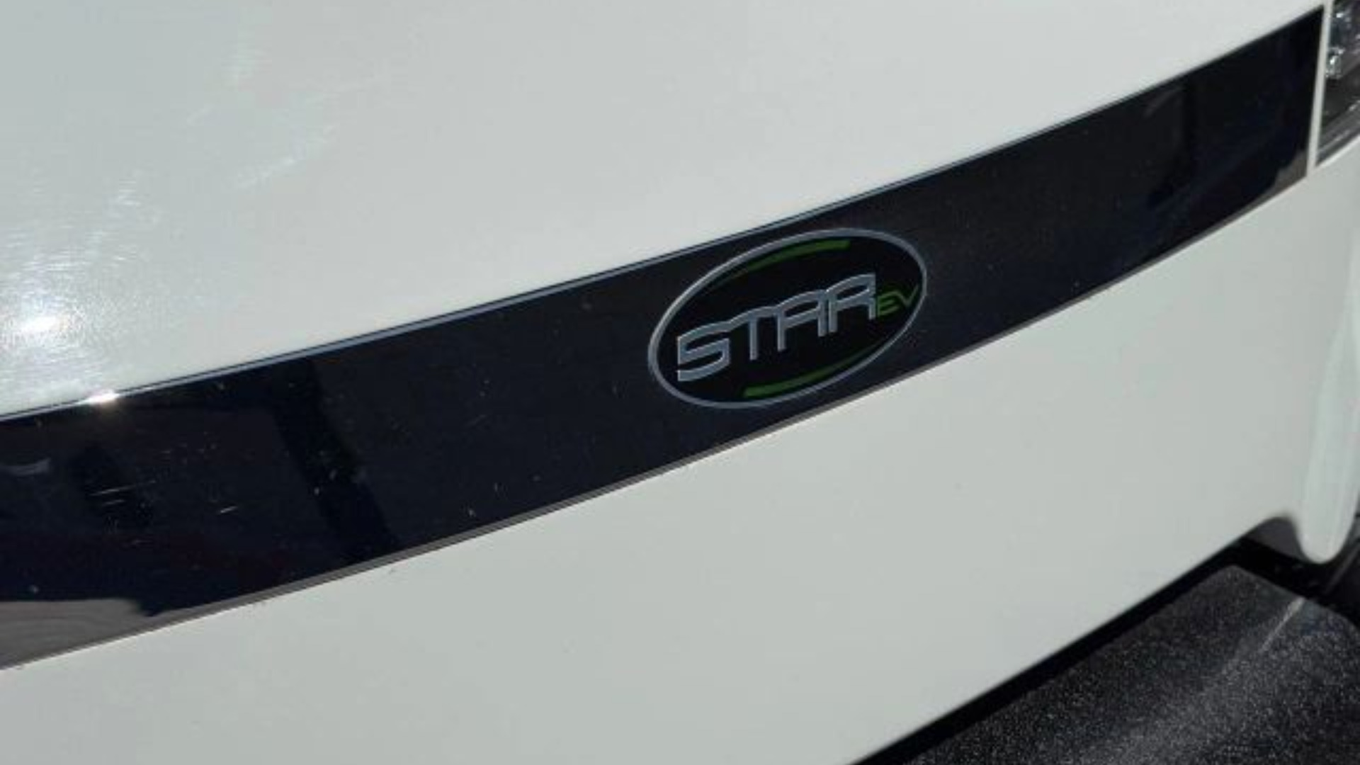 Close-up of STA EV badge on the white exterior panel of a golf cart.