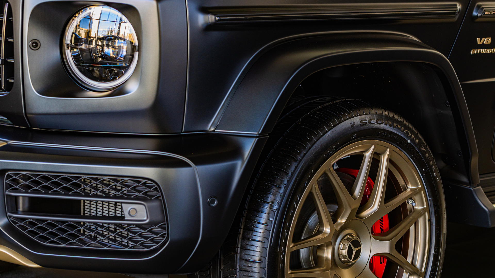 Close-up of a black luxury SUV wheel, headlight, and front fender detail.