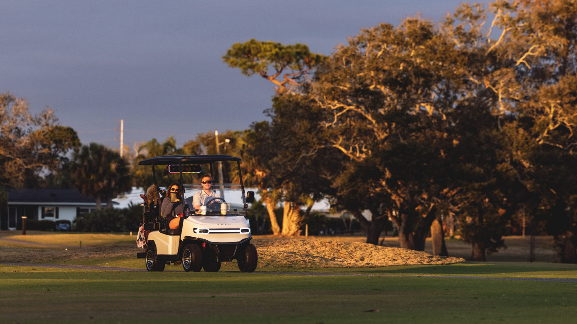 2026 Teko Turbolite golf cart on Phoenix course at sunset with two passengers.