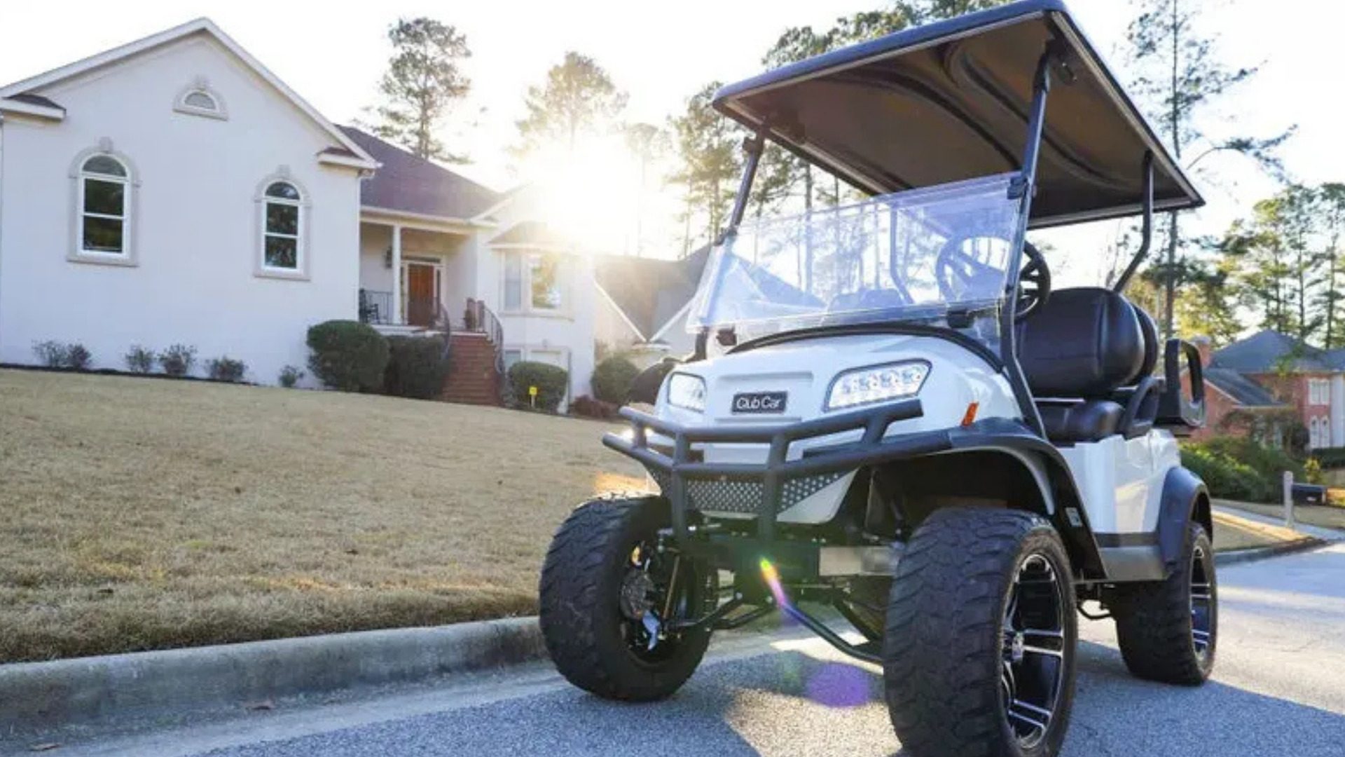 White Club Car golf cart parked in front of a suburban home.