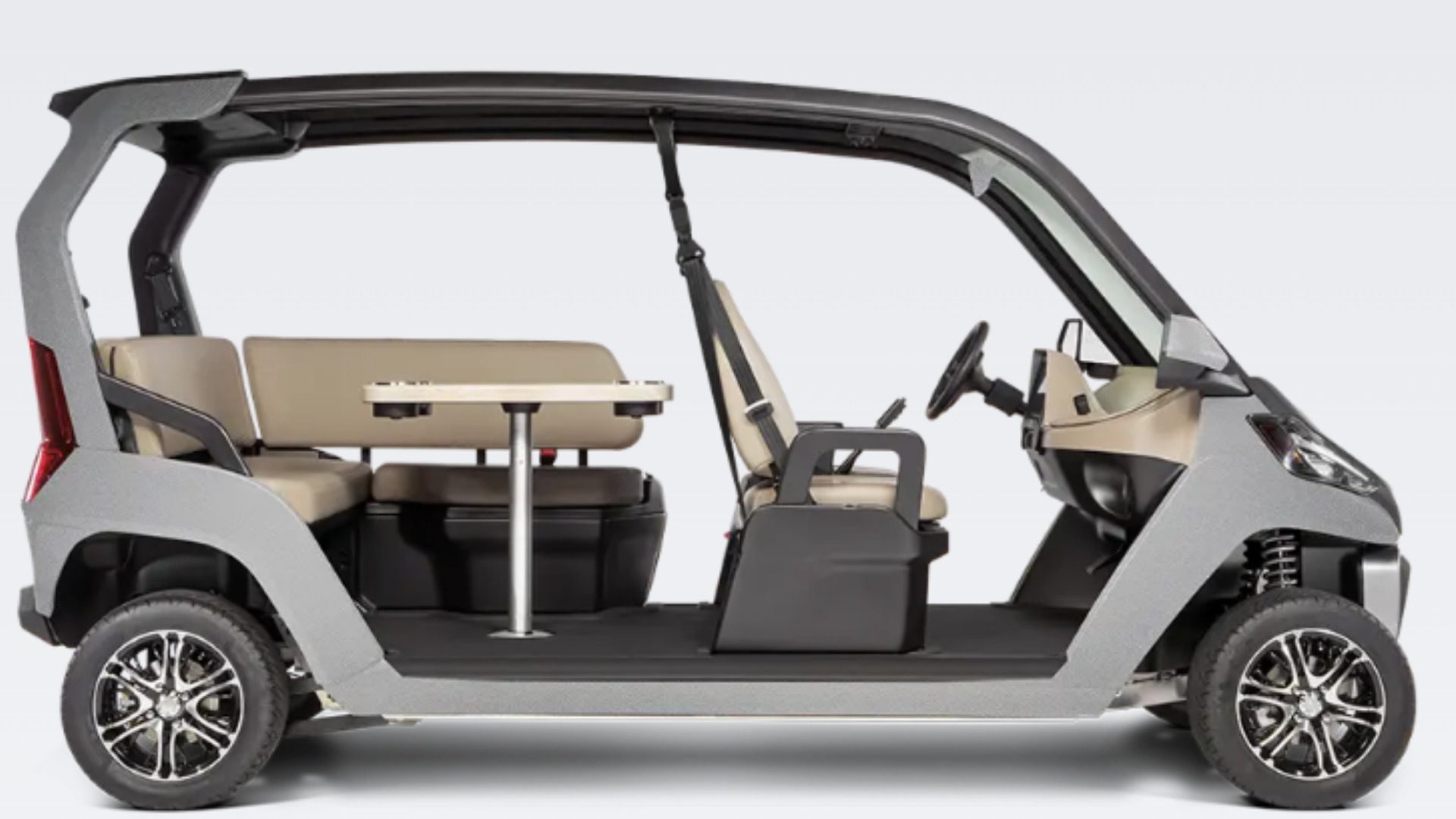 Gray enclosed low-speed vehicle with table seating shown in side profile.