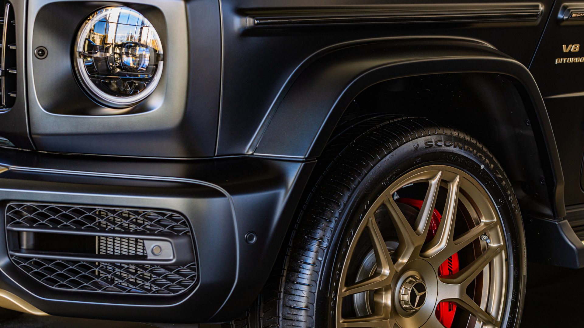 Close-up of a black luxury SUV wheel, headlight, and front fender detail.