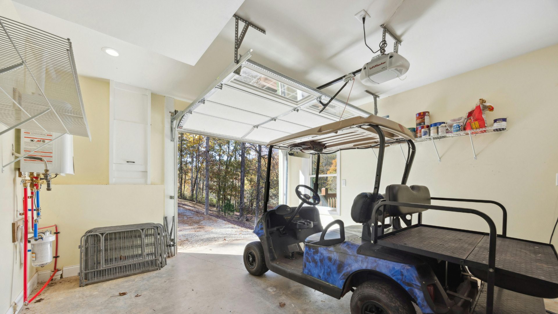 Blue utility golf cart parked inside a residential garage with the garage door open.